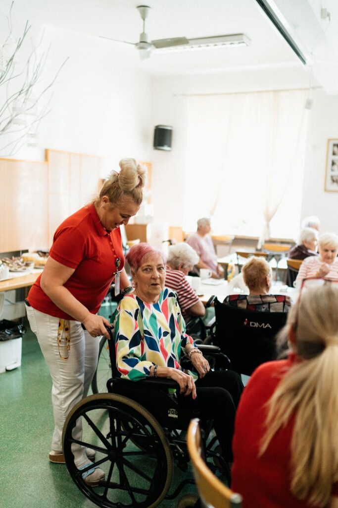 Pečovatelka se stará o seniorku ve společenské místnosti